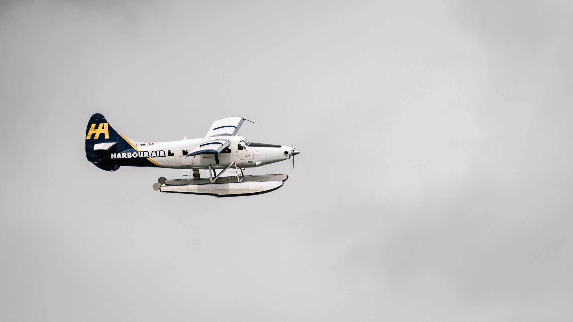 Harbour Air floatplane flying across a pale clouded sky near Vancouver