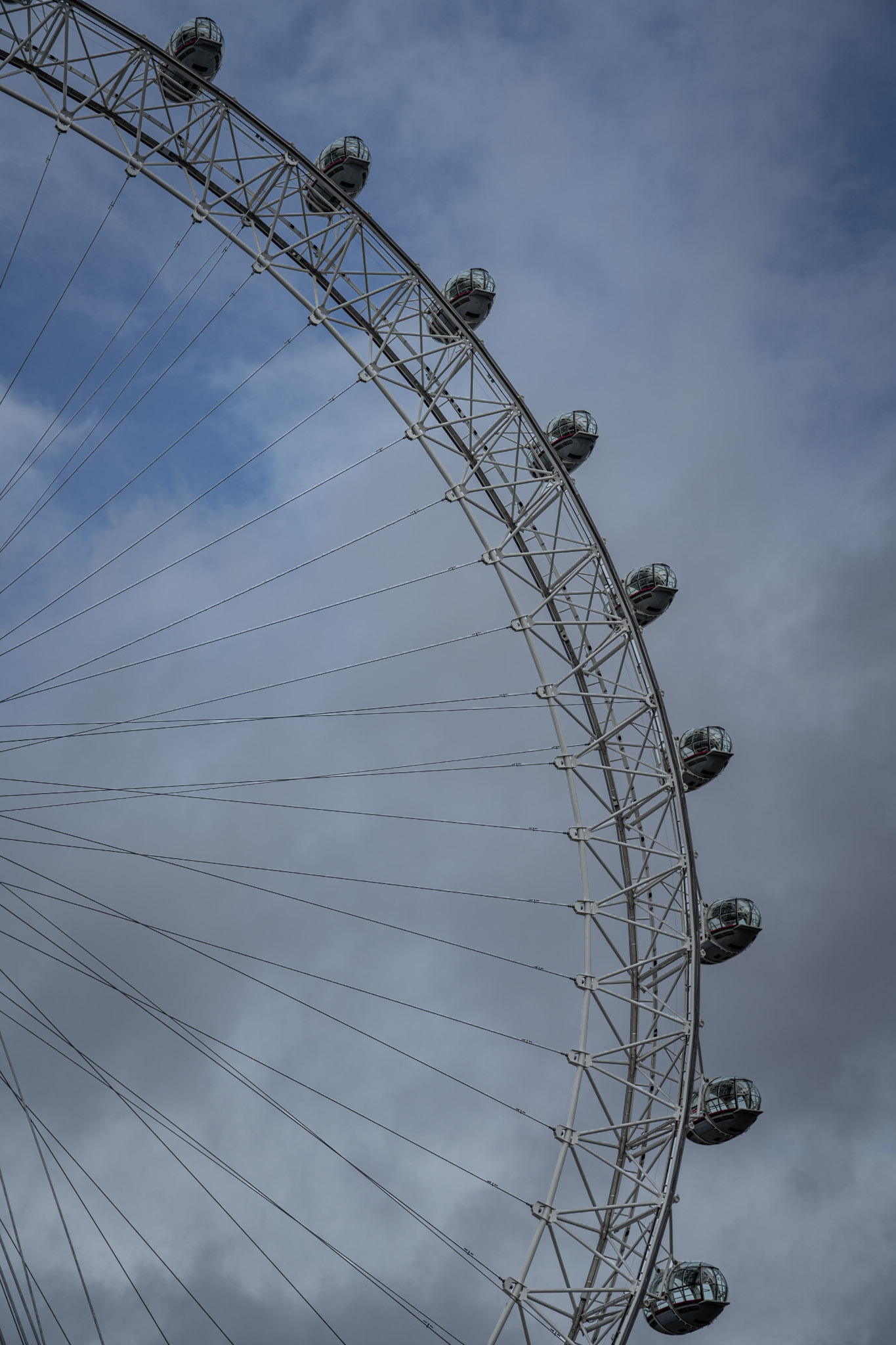 Upper arc of the London Eye crossing a layered gray-blue sky