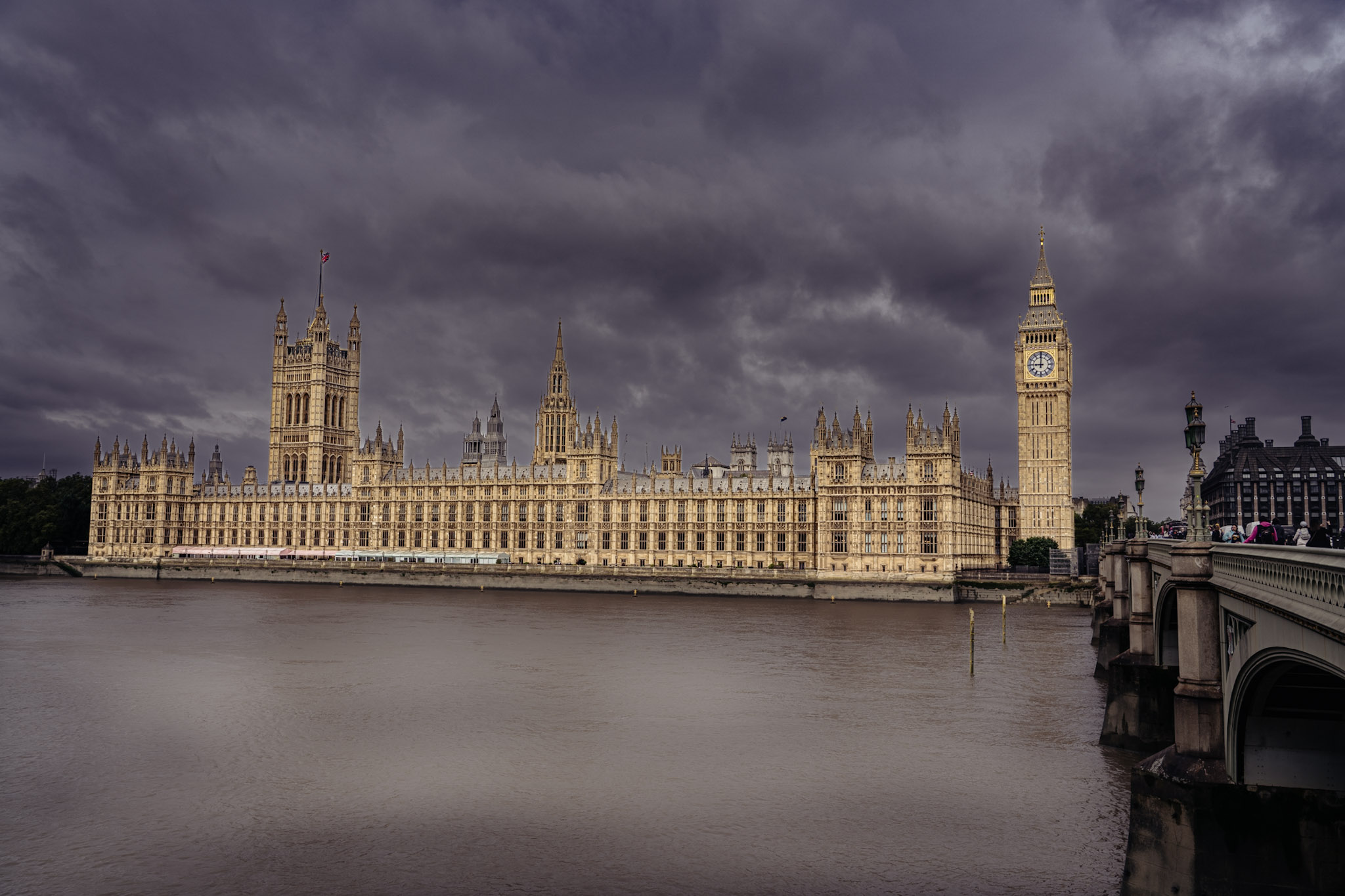 Palace of Westminster and Elizabeth Tower across the River Thames beneath dark layered clouds