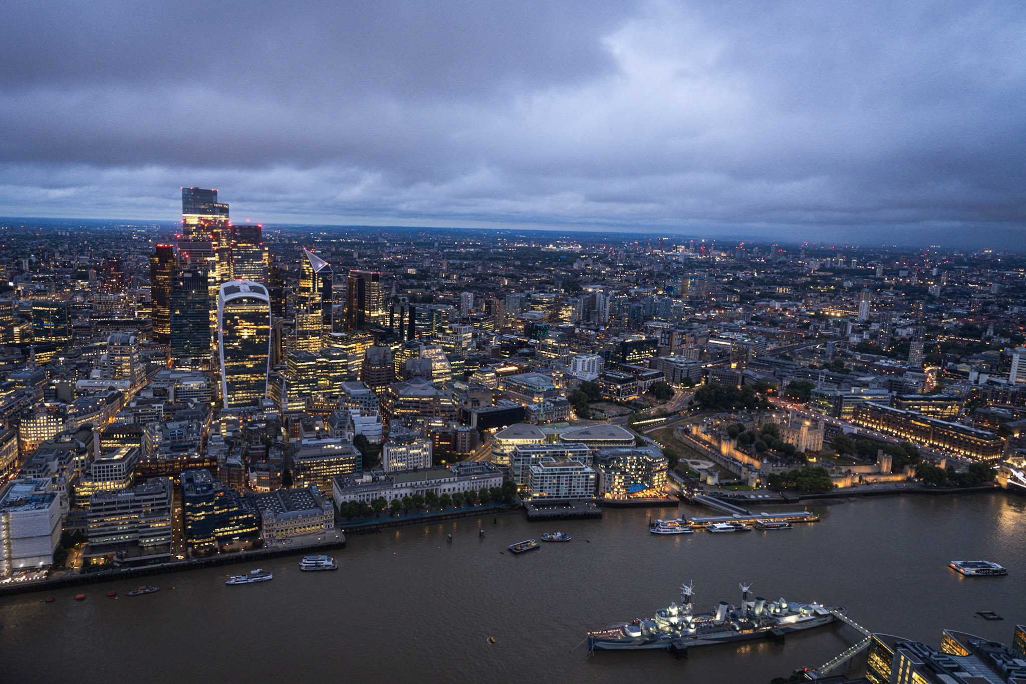 City of London skyline and River Thames seen from above beneath a low blue-gray cloud bank