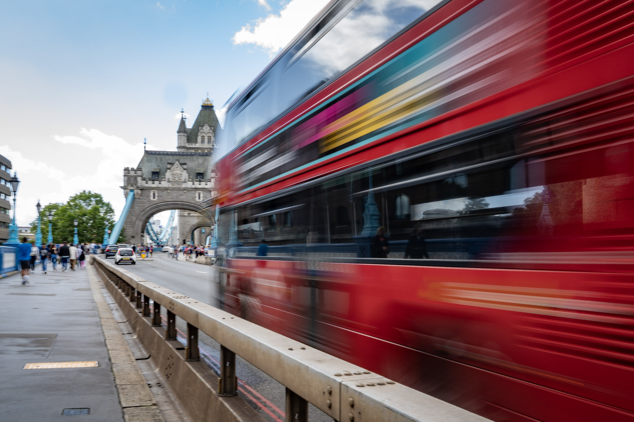 Red double-decker bus blurred in motion as it crosses Tower Bridge in London