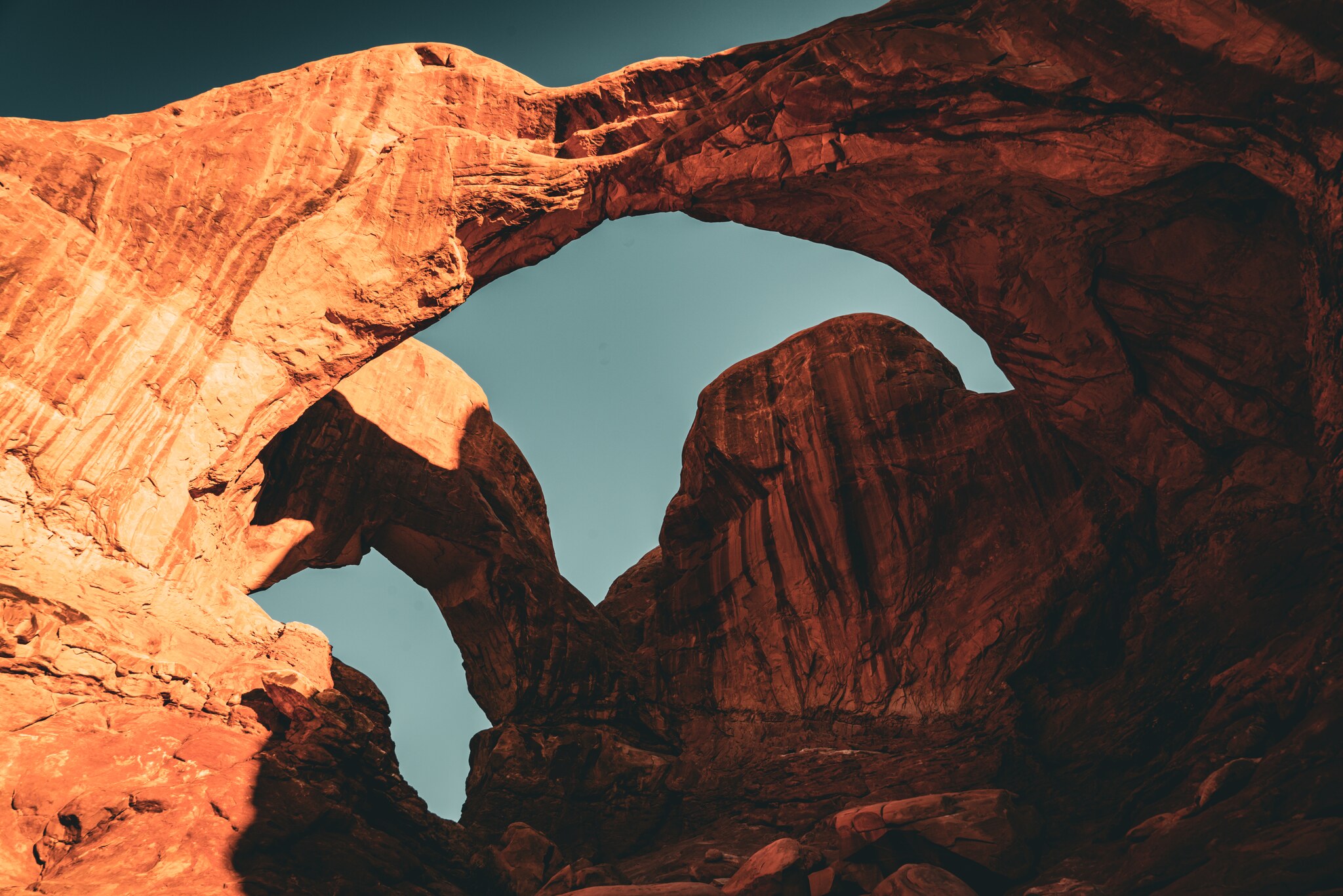 Overlapping openings and red sandstone walls seen from beneath Double Arch against blue sky