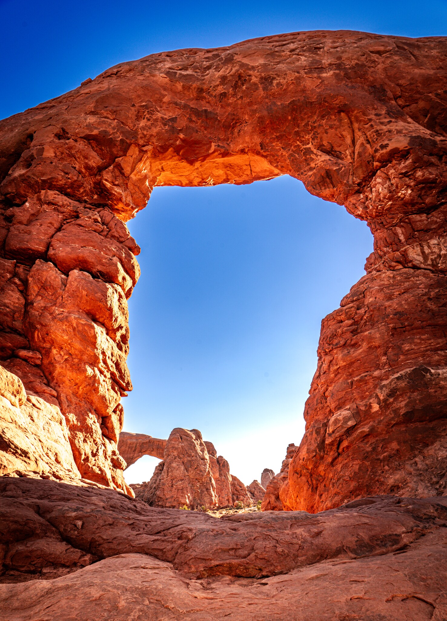 Turret Arch and blue sky framed by the glowing red interior of North Window